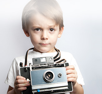kleiner Junge mit analoger Kamera in Händen