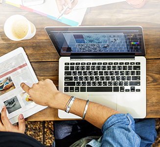 Laptop auf Tisch mit Händen und Tablet