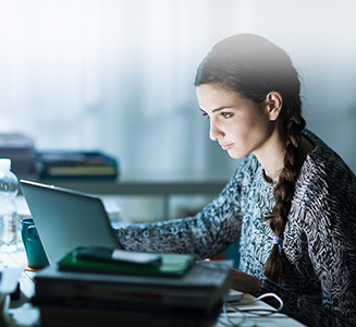 Frau sitzt an Tisch vor Laptop