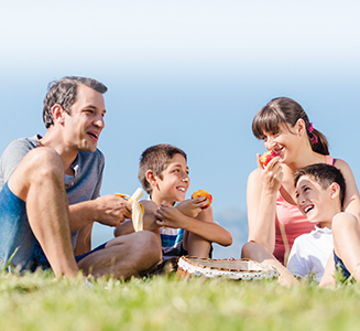 Glückliche Familie isst Piknik auf Wiese