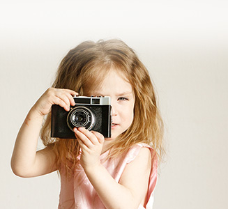 Kleines Mädchen mit analoger Kamera in Händen