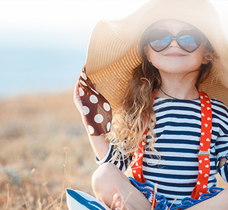 Kleines Mädchen mit Hut und Sonnenbrille auf Feld