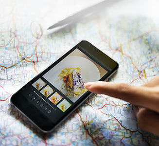 Person zeigt auf Smartphone mit Landkarte im Hintergrund