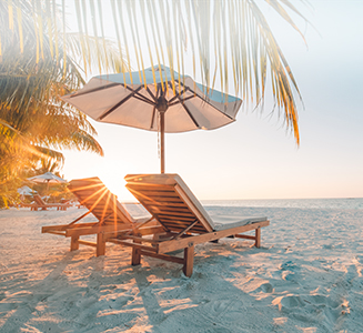 Liegestühle mit Sonnenschirm am Strand und Sonnenuntergang